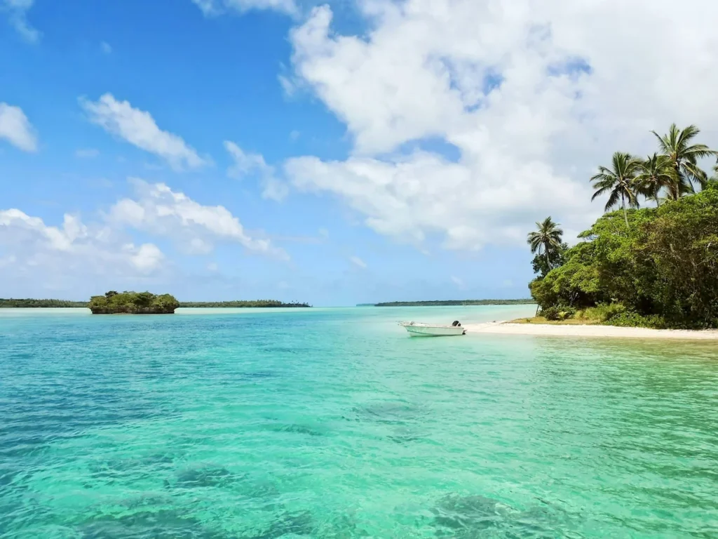A small boat anchored beside the sandy shore of Monkey Island in Port Antonio, Jamaica