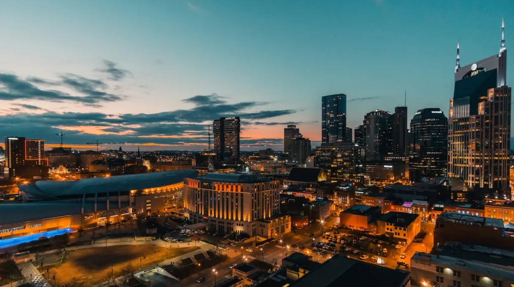 Wide drone view of the Nashville skyline at sunset with the AT&T building lit up