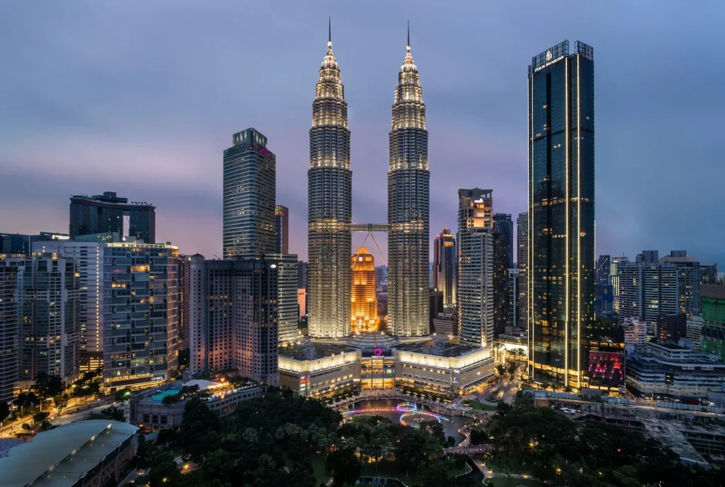 Illuminated Petronas Twin Towers soaring over the Kuala Lumpur city skyline at dusk