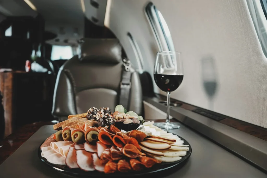 Charcuterie platter and glass of red wine on a table inside a private jet cabin