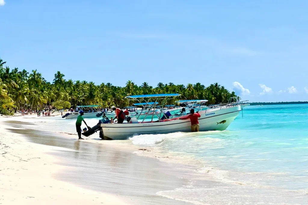 Tour boats anchored along a white sand beach in Saona Island