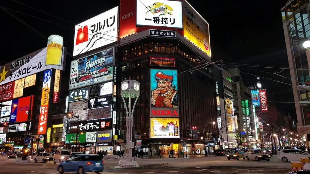 The iconic Nikka Whisky sign and vibrant billboards at a street intersection in Susukino, Sapporo