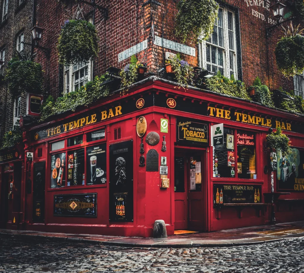 The famous red exterior of The Temple Bar on a cobblestone street corner in Dublin