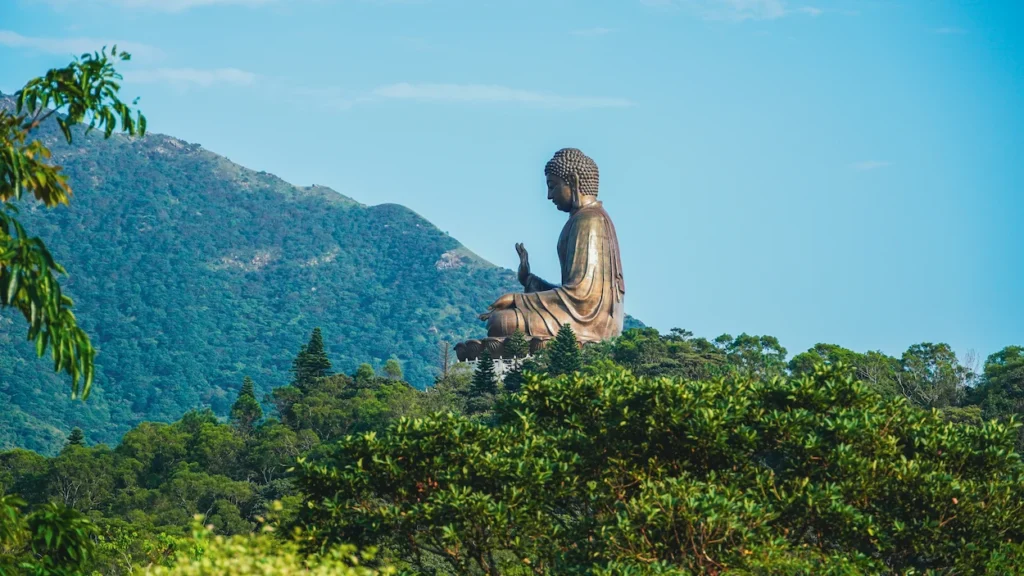 Large bronze Tian Tan Buddha statue sitting on a hill surrounded by green trees