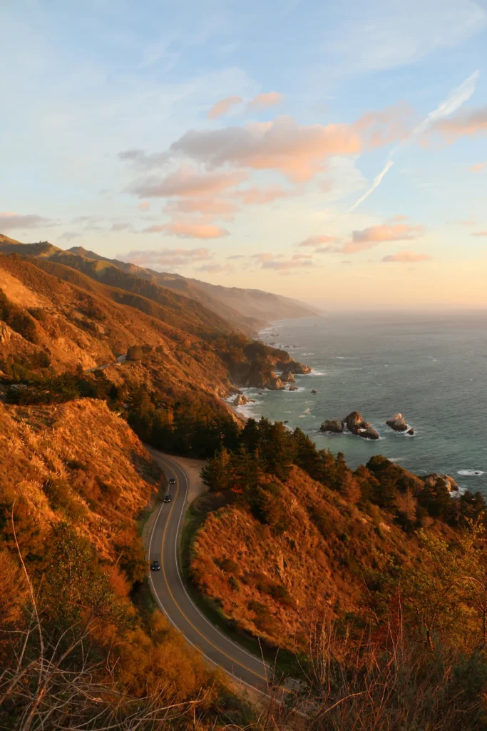 Winding Pacific Coast Highway curves along steep Big Sur cliffs overlooking the ocean at sunset