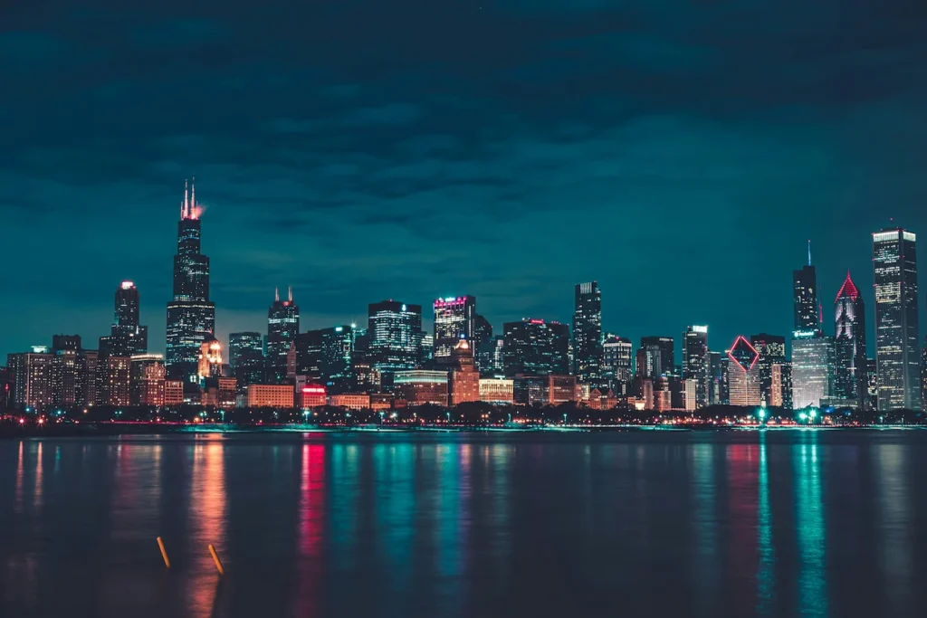 Chicago skyline illuminated at night reflecting across Lake Michigan