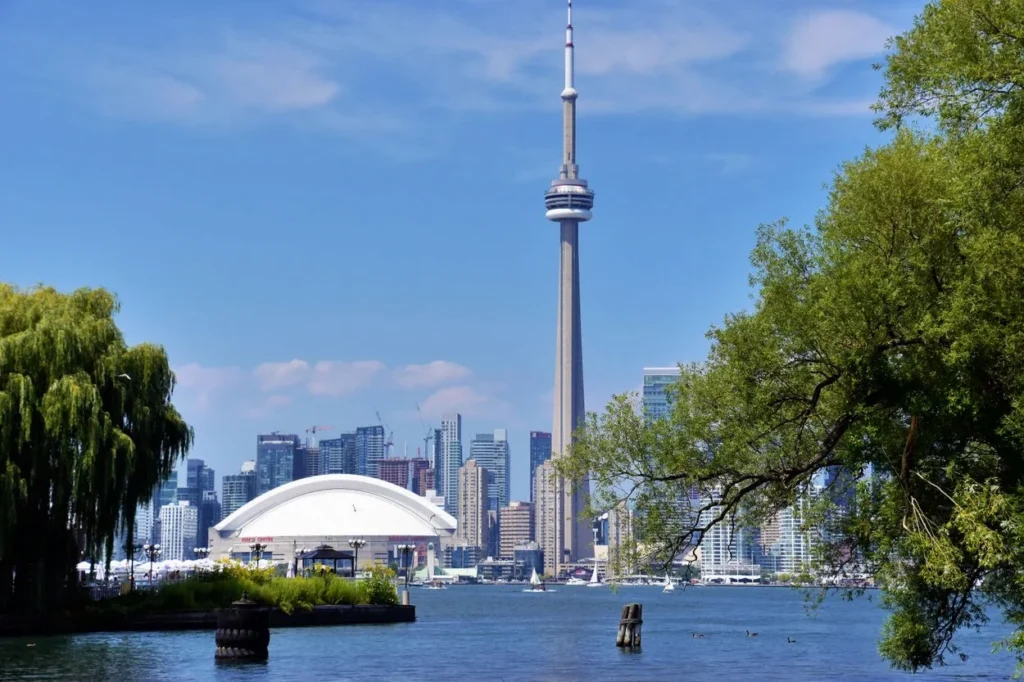 CN Tower and Rogers Centre dome viewed across the water framed by green trees