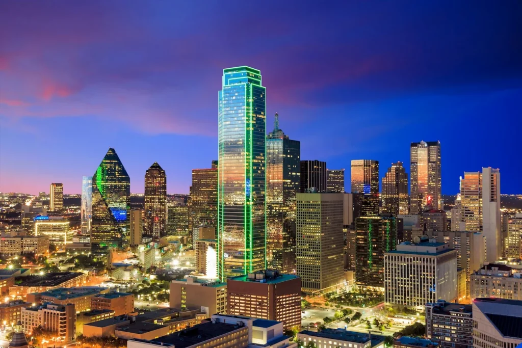 Downtown Dallas skyline at night featuring the green neon-lit Bank of America Plaza