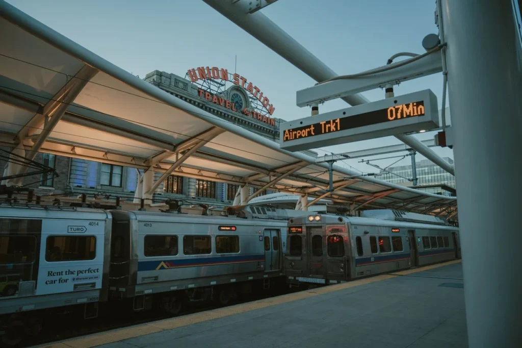 Commuter trains parked at the outdoor platform under the Denver Union Station canopy