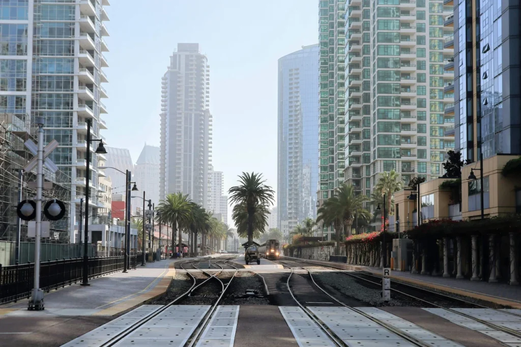 San Diego Trolley train on steel tracks running through downtown streets lined with modern high-rises