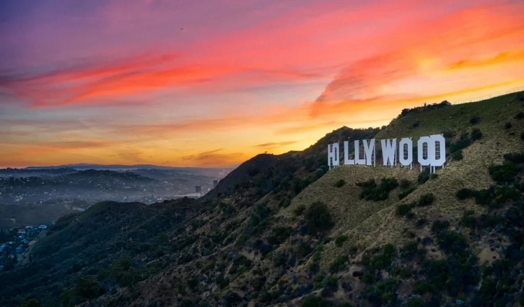 Hollywood Sign on a grassy hillside overlooking Los Angeles during a vibrant sunset