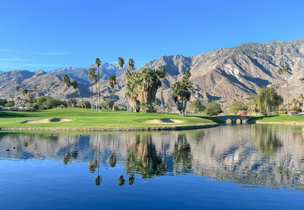 Palm Springs golf course green and mountain reflection on a calm water hazard lake