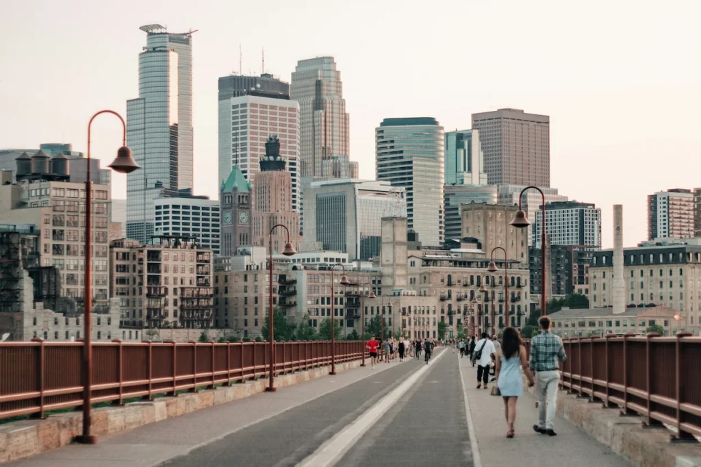Pedestrians walking on the Stone Arch Bridge toward the Minneapolis city skyline