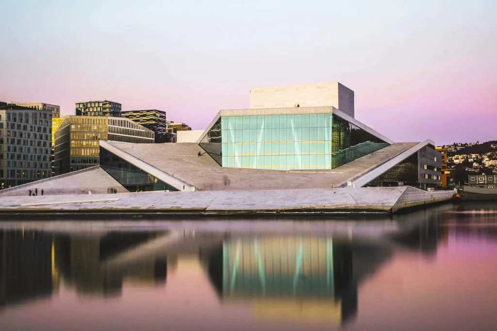 The modern white marble and glass Oslo Opera House reflecting in the calm waterfront at dusk