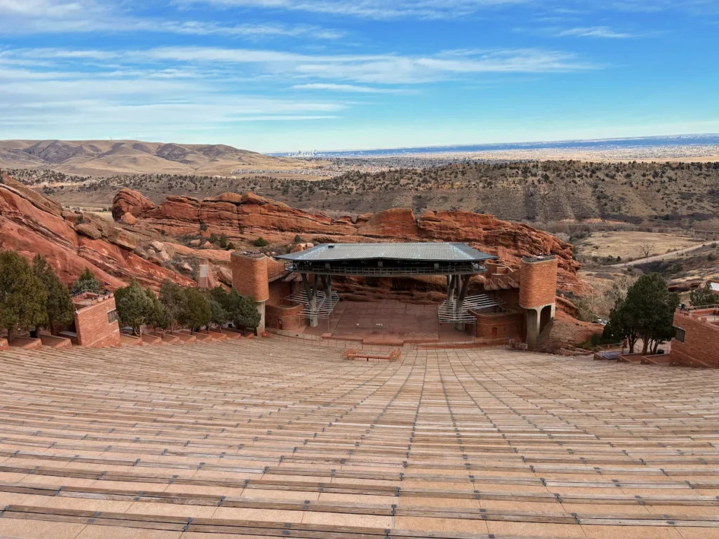 Empty amphitheater seating looking down at the stage surrounded by red rock formations