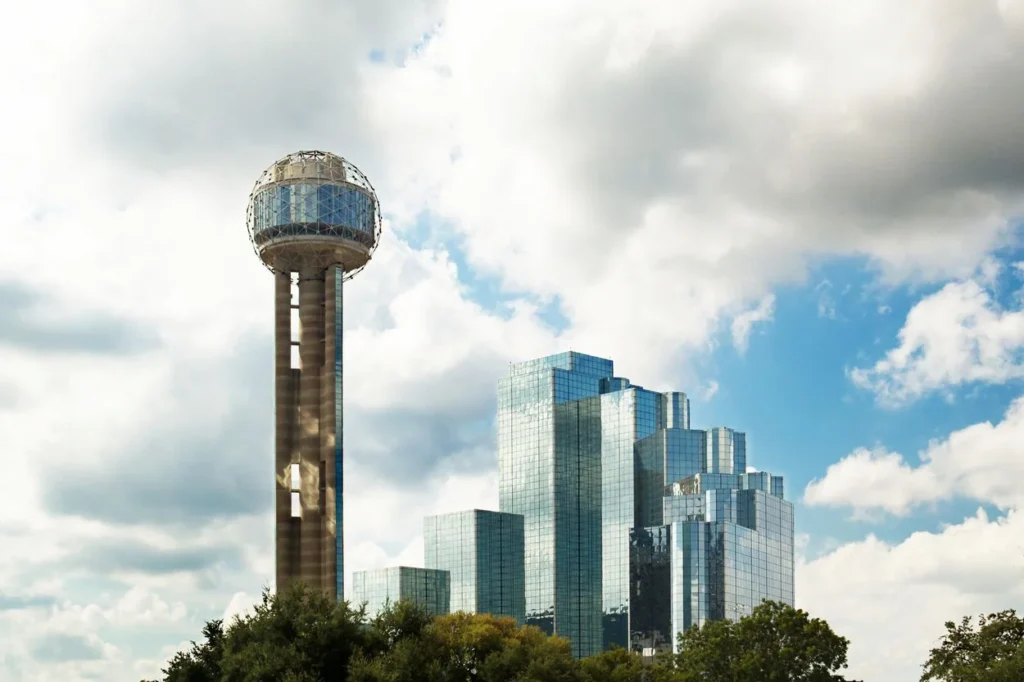 Reunion Tower standing next to the mirrored glass facade of Hyatt Regency Dallas
