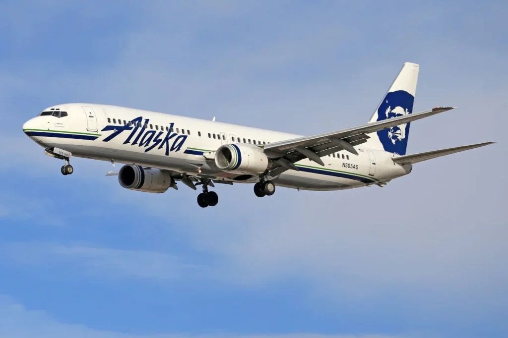 Alaska Airlines Boeing 737 passenger jet descending against a blue and white sky