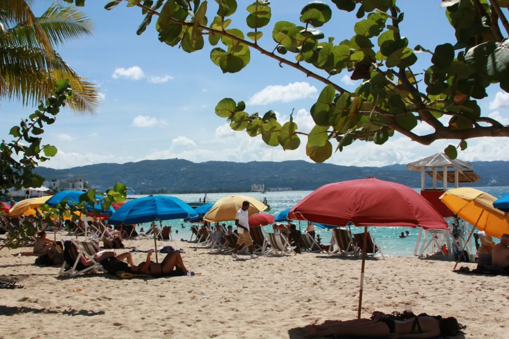 A crowded beach with colorful umbrellas and chairs facing the ocean