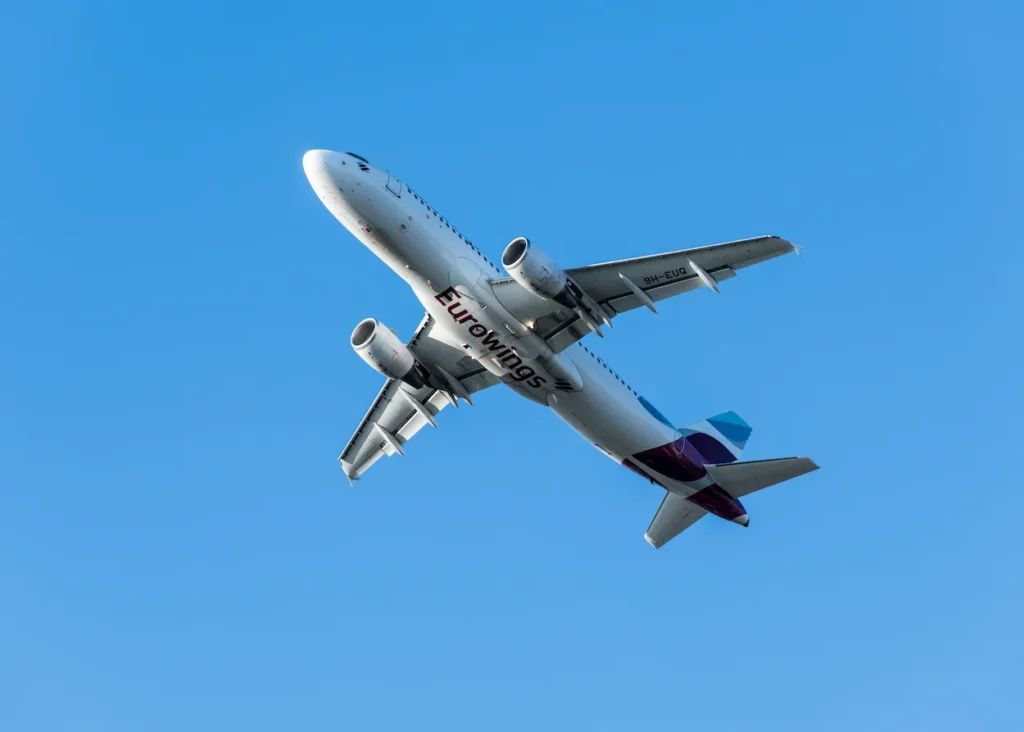 A Eurowings Airbus A320 commercial airplane flying low in a clear blue sky