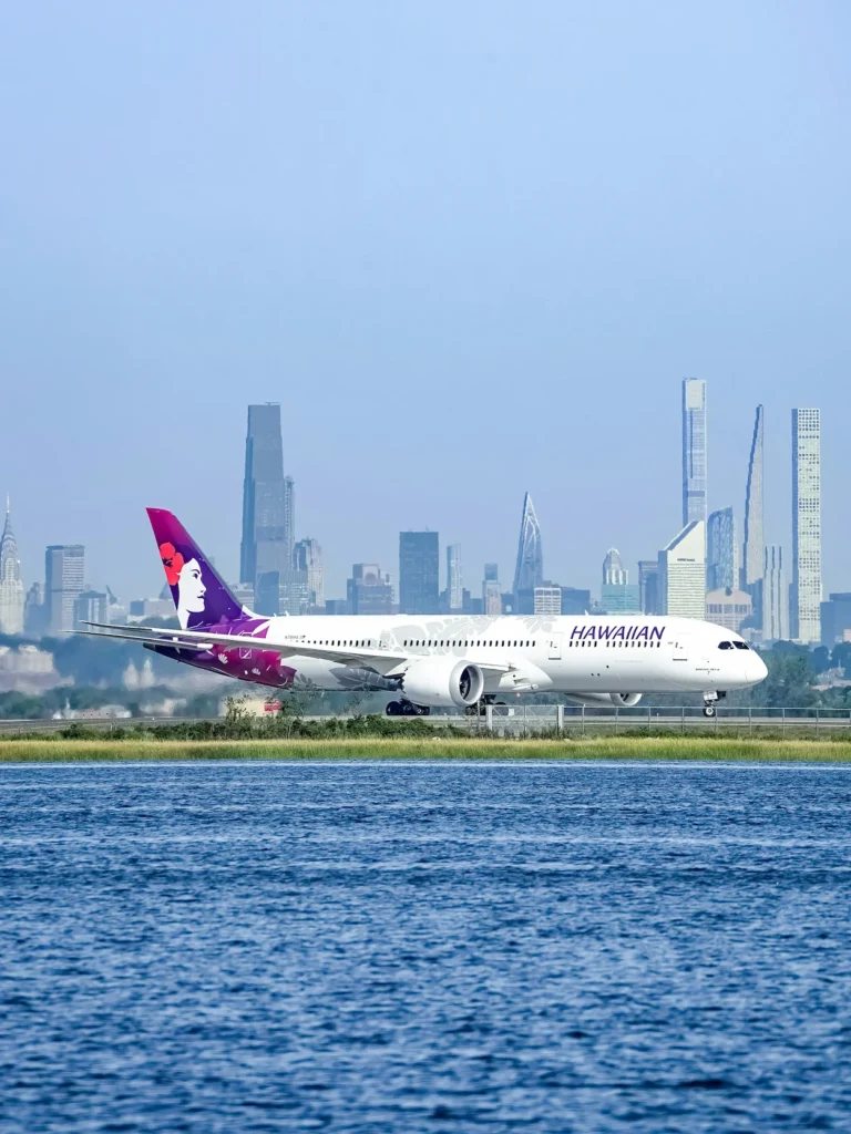 Hawaiian Airlines Boeing 787-9 Dreamliner on a runway with the New York City skyline across the water