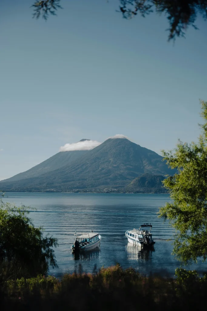 Two small motorboats floating on Lake Atitlán with a large volcano in the background