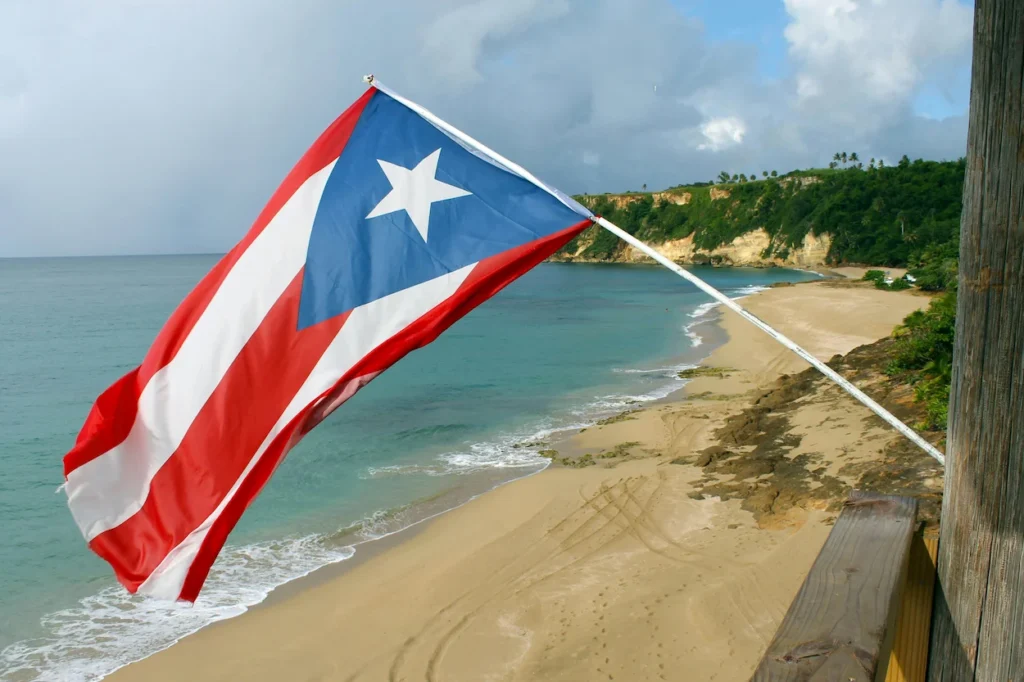 The Puerto Rican flag waving over a sandy beach and turquoise ocean