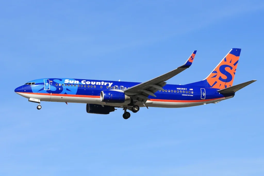Sun Country Airlines Boeing 737 passenger airplane flying in a clear blue sky