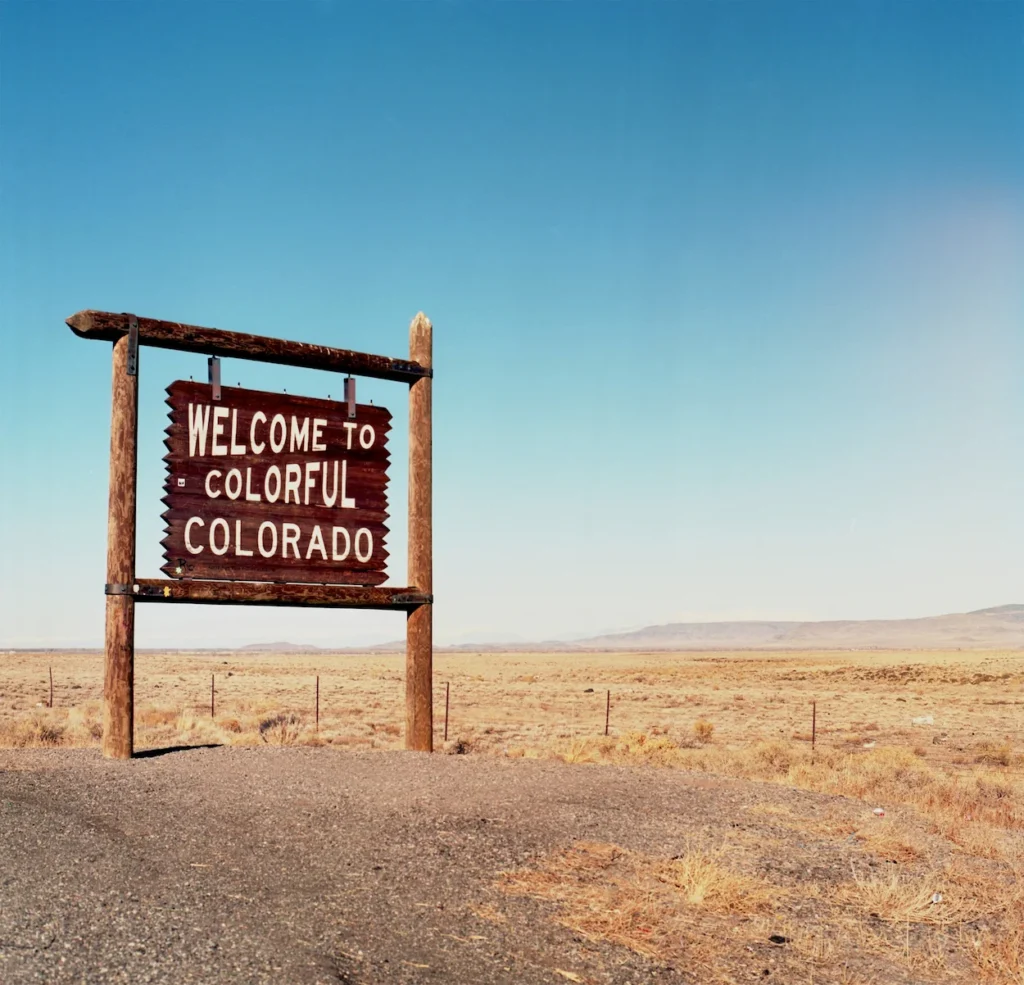 The wooden Welcome to Colorful Colorado sign standing in a desert landscape