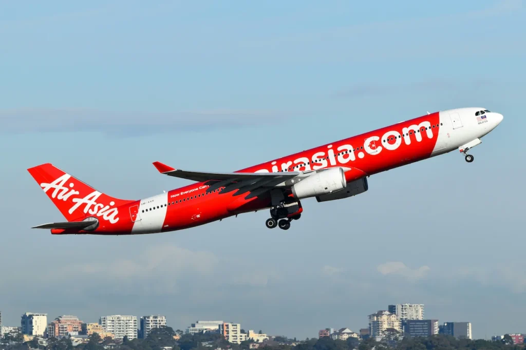 AirAsia Airbus A330 passenger airplane taking off over a city skyline