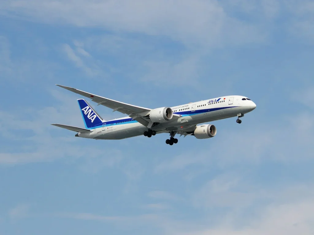 An All Nippon Airways (ANA) Boeing 787 airplane flying through a light blue sky