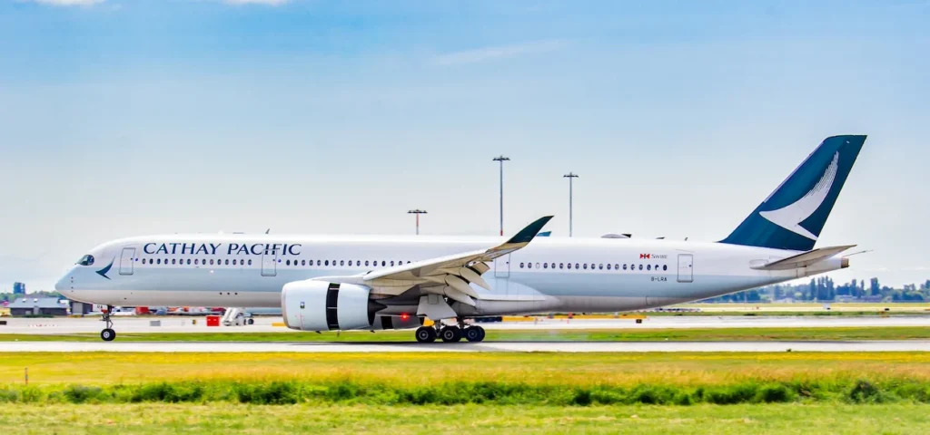 Cathay Pacific Airbus A350 passenger jet on an airport runway with grassy field background