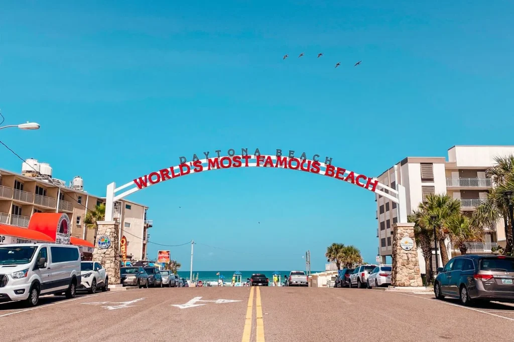 The iconic "World's Most Famous Beach" arch sign over a road leading to the ocean in Daytona Beach