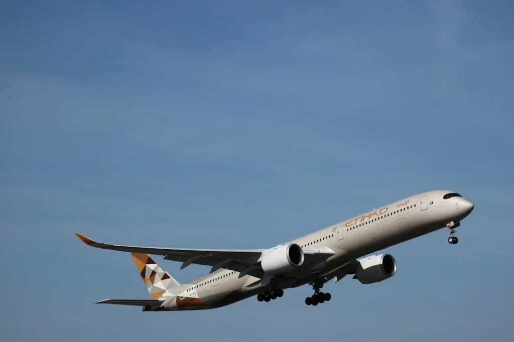 An Etihad Airways Airbus A350-1000 long-haul widebody aircraft ascending into a clear blue sky right after takeoff