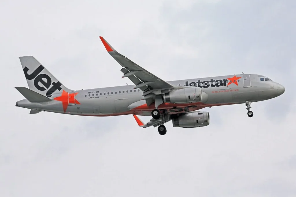 Jetstar Airbus A320 descending with landing gear down under an overcast sky
