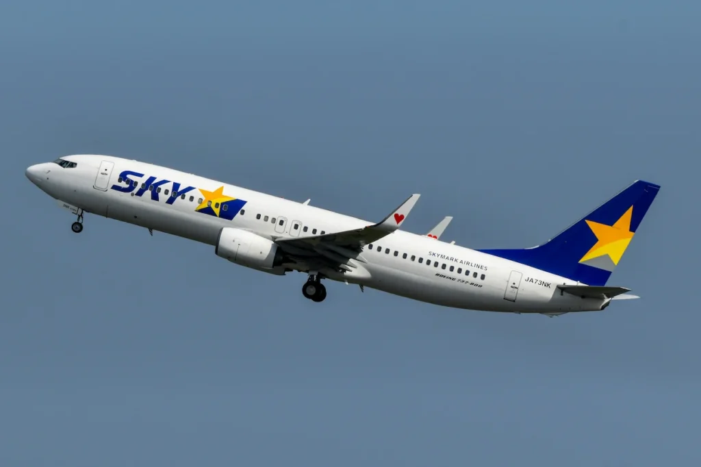 Skymark Airlines Boeing 737-800 climbing into a clear blue sky after takeoff