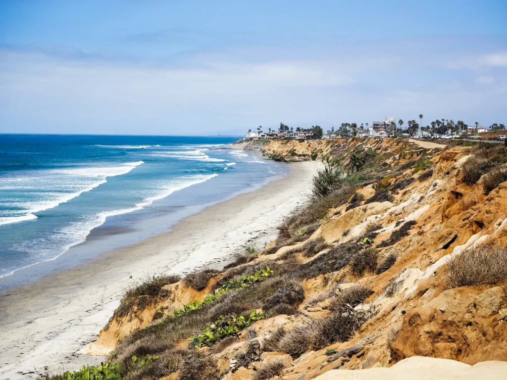 A high-angle view looking down at the long sandy shoreline of South Carlsbad State Beach