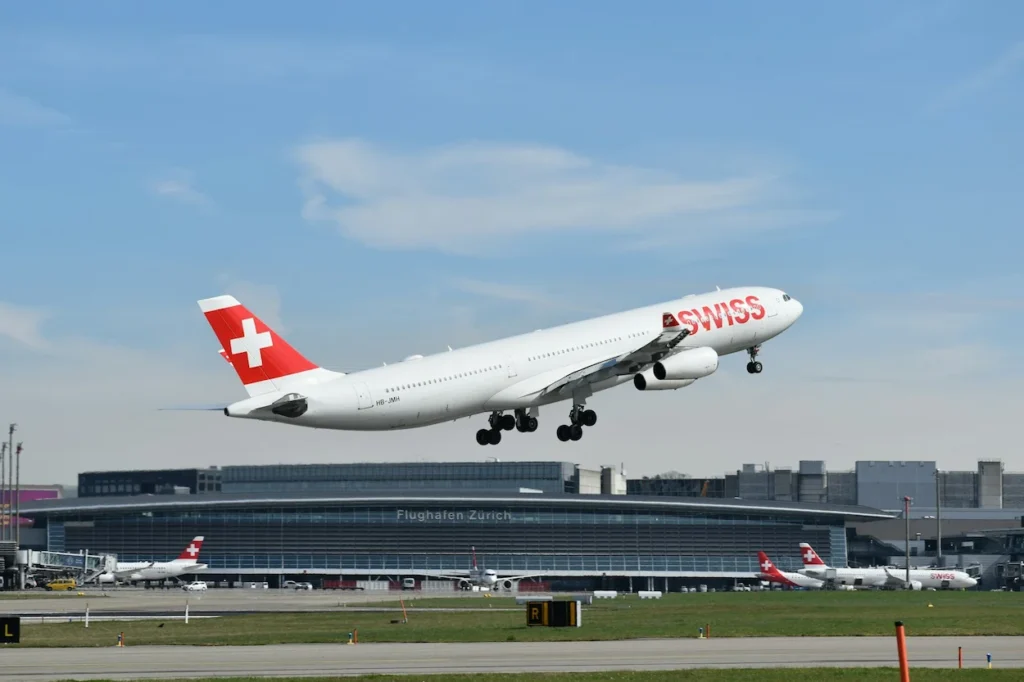A four-engine SWISS Airbus A340 airliner climbing into the sky above Zurich Airport
