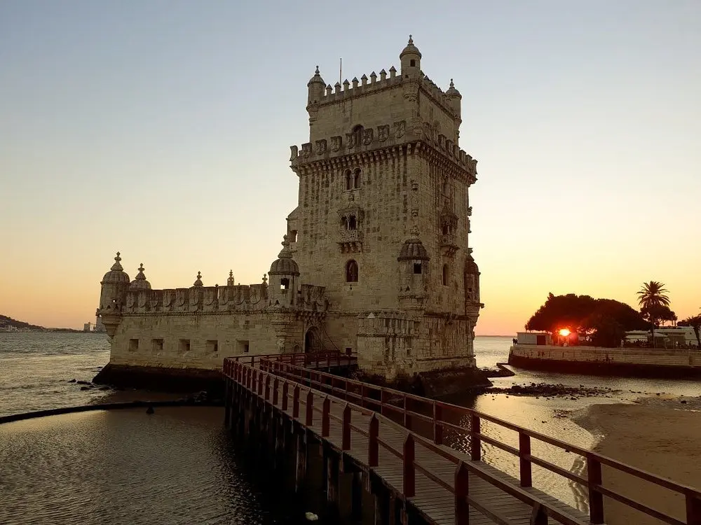 The stone Belém Tower on the waterfront in Lisbon at sunset.