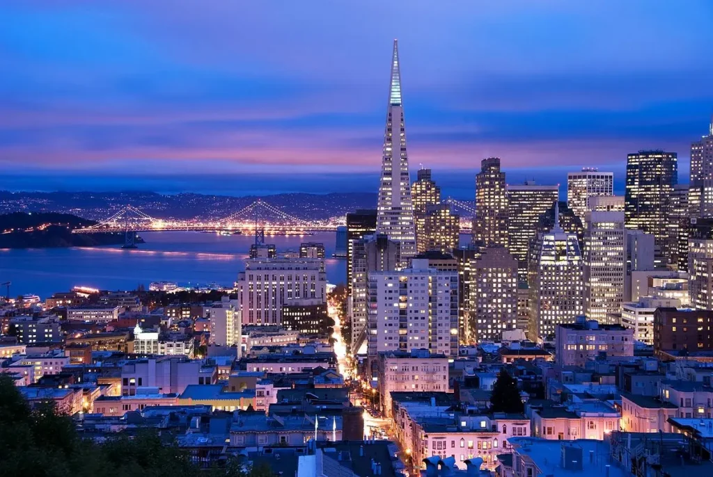 The San Francisco skyline at dusk with the Bay Bridge in the background.