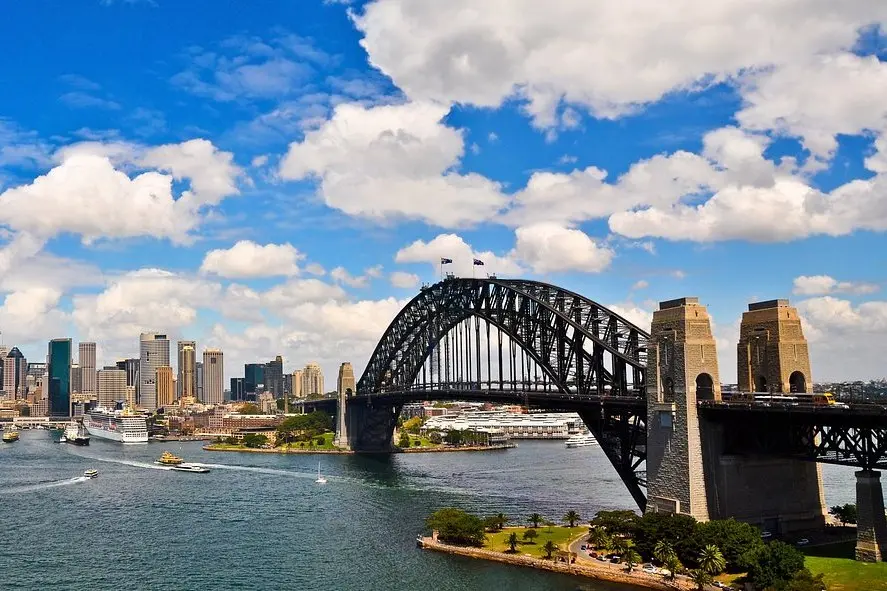 The Sydney Harbour Bridge stretches across the water with the city skyline in the background.