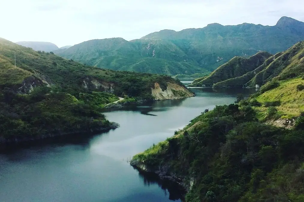 A peaceful river winds through green mountains in the countryside of Colombia.