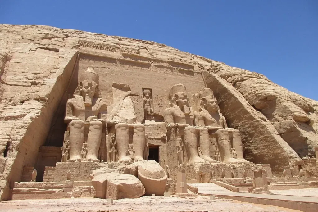 Ancient statues of Pharaoh Ramses II sit at the entrance of the Abu Simbel temples carved into a rock cliff in Egypt.