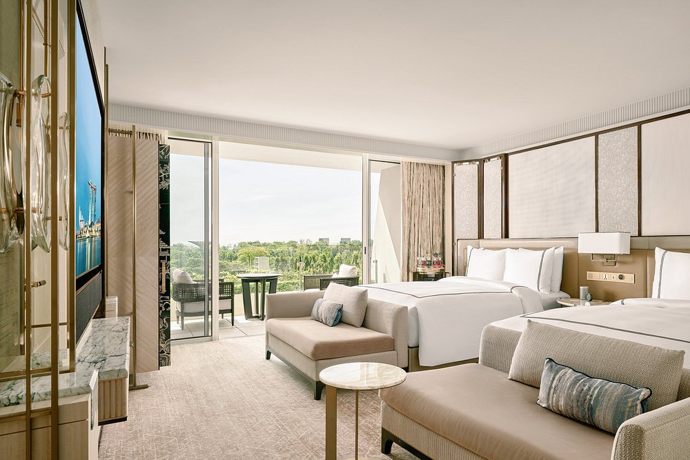 Marina Bay Sands hotel room with two beds, sofa seating, and balcony view.