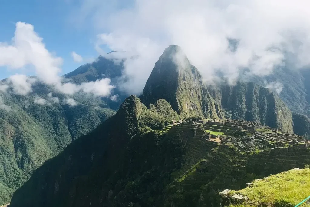 Ancient Incan ruins of Machu Picchu sit atop a mountain ridge surrounded by clouds in Peru.