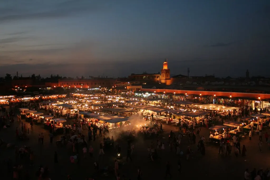 The Jemaa el-Fnaa market in Marrakech, Morocco is lit up at night with food stalls and crowds.