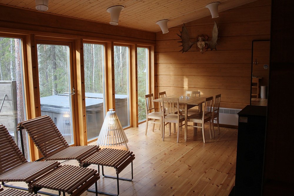 Treehotel cabin interior with wooden walls, dining table, lounge chairs, and forest view windows.