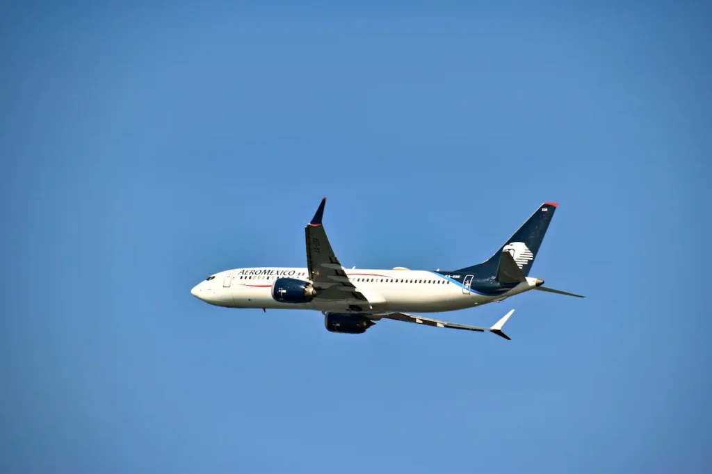 An Aeroméxico Boeing 737 MAX 8 passenger airplane flying upward through a clear blue sky