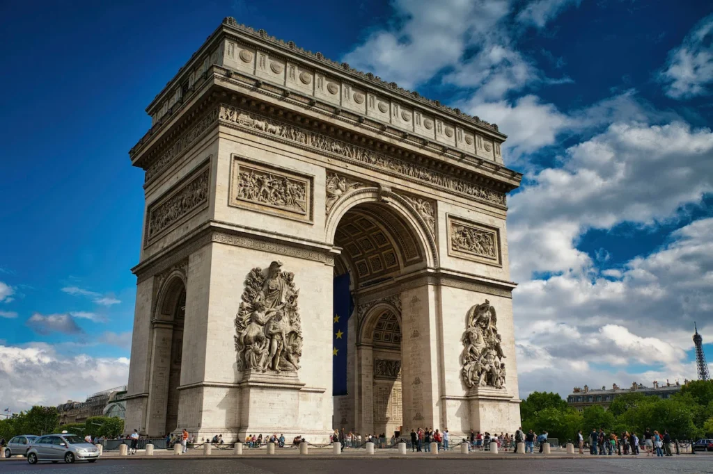 The historic Arc de Triomphe monument under a blue sky with white clouds in Paris