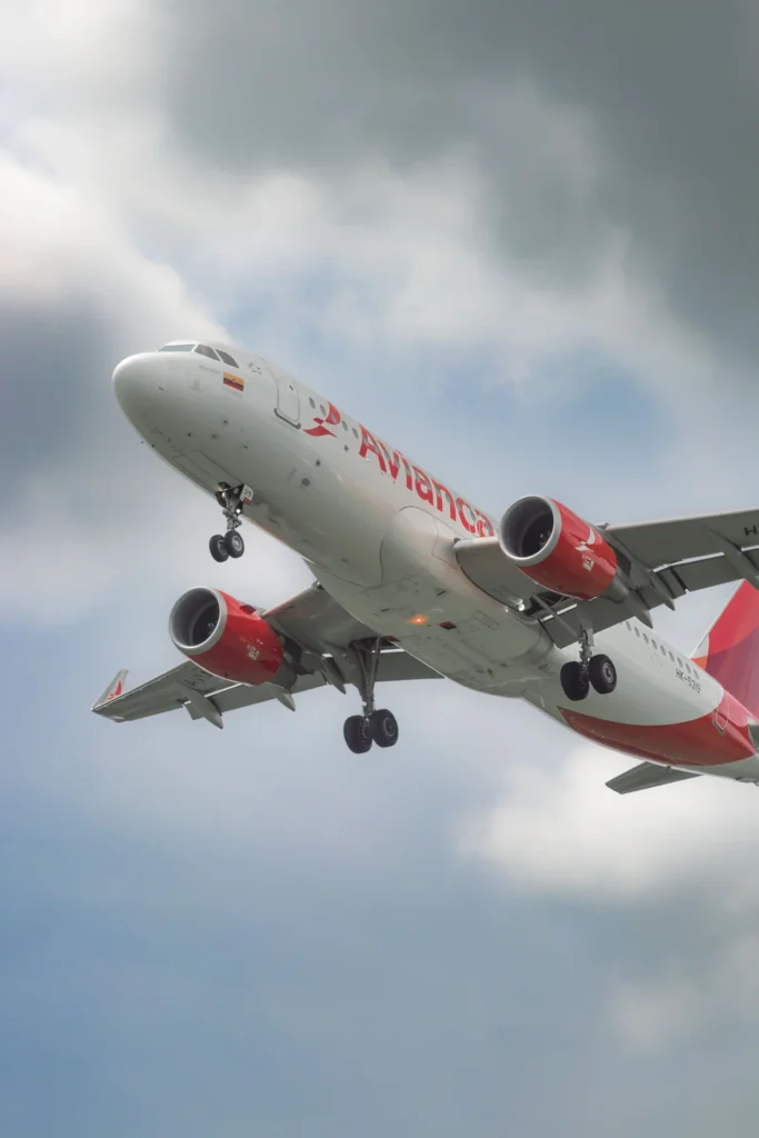 An Avianca Airbus A320 passenger airplane flying overhead with its landing gear down