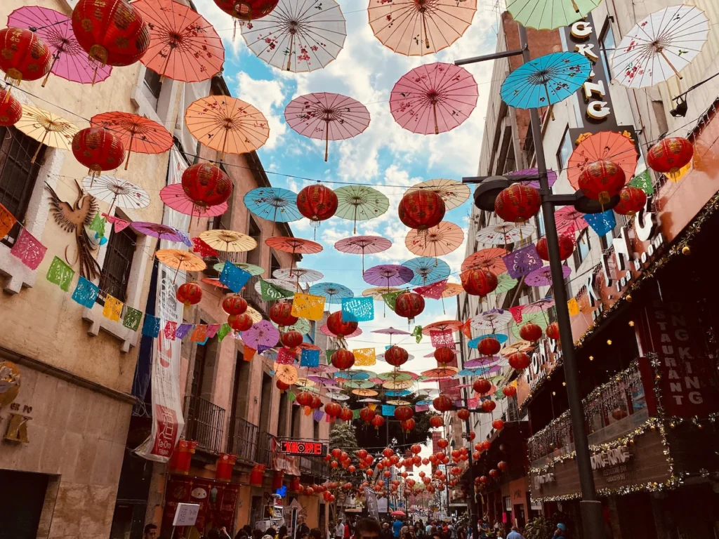 Colorful paper umbrellas and red lanterns hanging above a busy street in Chinatown, Mexico City